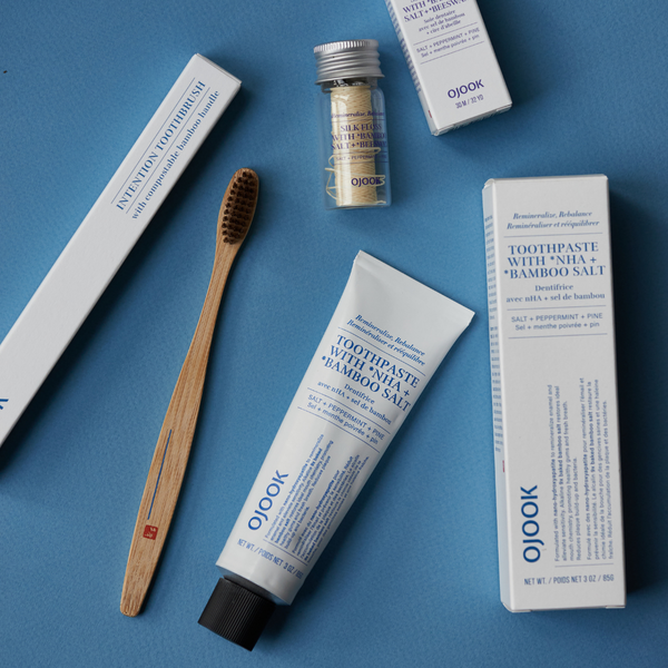 Bamboo salt toothpaste, silk floss and bamboo handle toothbrush in blue background explaining why Korean Oral care is the next K-Beauty Skincare 