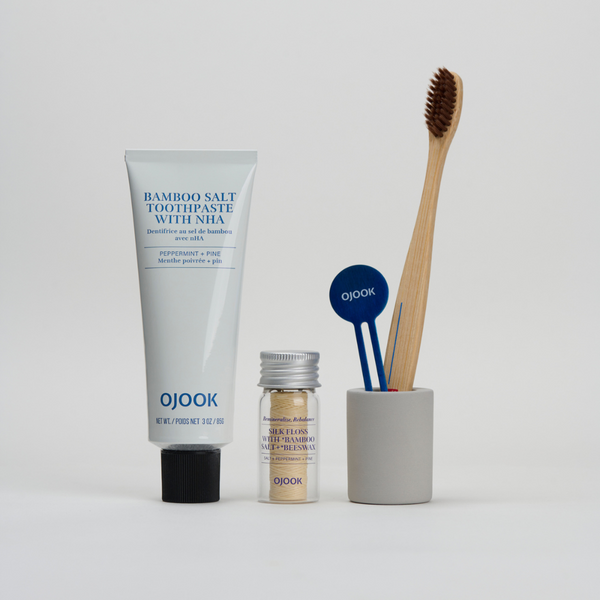 Bamboo salt toothpaste, silk floss and bamboo handle toothbrush in blue background explaining why Korean Oral care is the next K-Beauty Skincare 